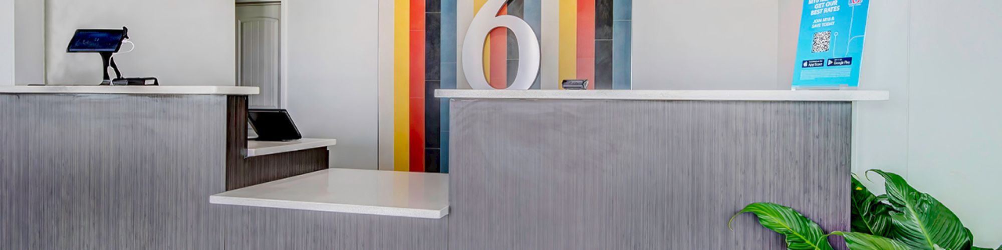 This is a modern, colorful hotel reception area with the number 6 prominently displayed on the wall behind the counter.